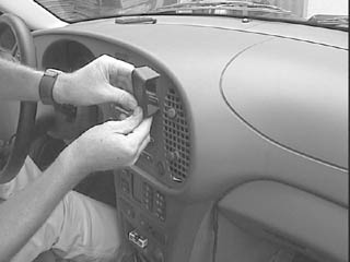 En person installerar en träpanel i en Saab 9-3:s mittkonsol.