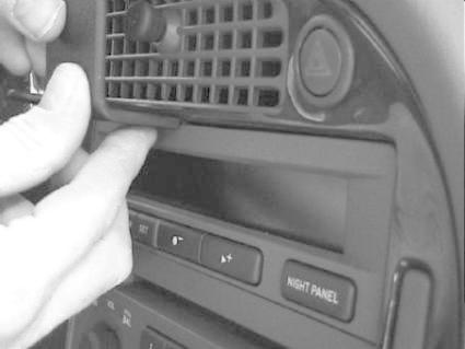 En hand installerar en träpanel i Saab 9-5's mittkonsol.