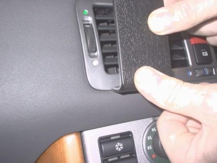 En hand håller i en svart ventilationslucka i en bil.