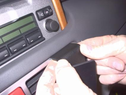 En hand fäster en svart del i en bilinterior.