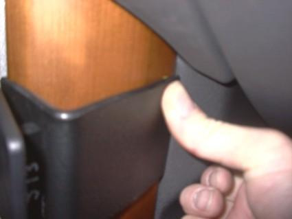 En hand som trycker på en del av en bils interiör, nära trädetalj.