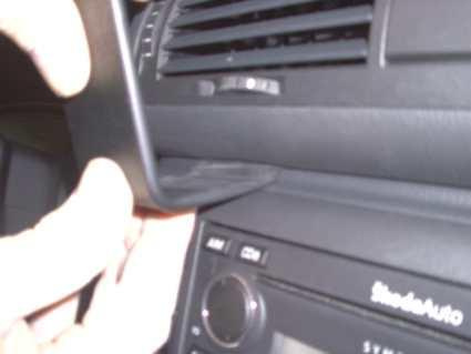 Bild på en bilinteriör med hand som justerar en del av instrumentpanelen.