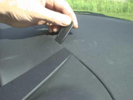 En hand håller en liten verktyg mot en bils instrumentpanel.