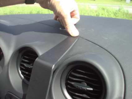 En hand trycker ner en besvärd del på instrumentpanelen i en bil.