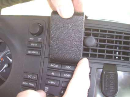 En hand håller en svart rem framför bilens instrumentpanel.