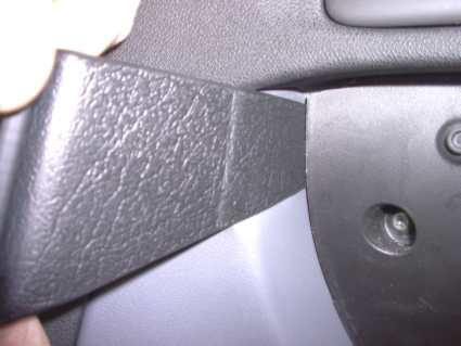 Svart plastdetalj från interiören på Saab 9-3, vinklad form.