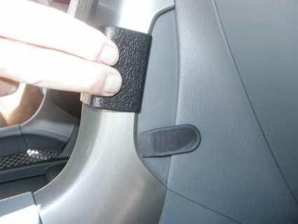 En hand håller i ett svart fäste på insidan av en bil.