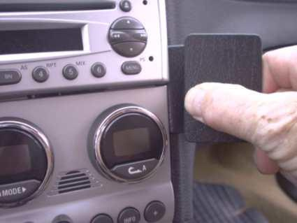 En hand som trycker på en enhet nära bilens stereo.