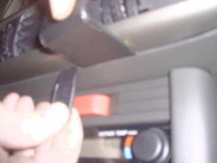 En hand som håller en nyckel mot en konsol i en bil.