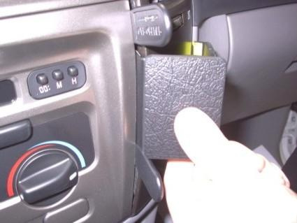 En hand som håller en svart plastbehållare i en bils interiör.