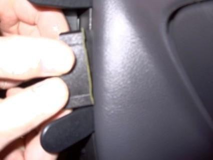 En hand som håller i en svart klämma nära en bilinteriör.