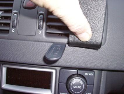 En hand håller i en panel med reglage i en bilinteriör.