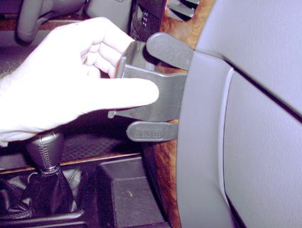 En hand håller en del som fästs på brun träpanel i Kia Sorento 02-07.