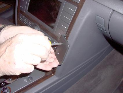 En hand som installerar en monteringsbygel i en bilinteriör.