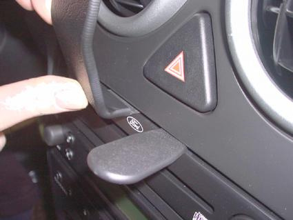 En hand som trycker på en knapp på bilens mittkonsol.