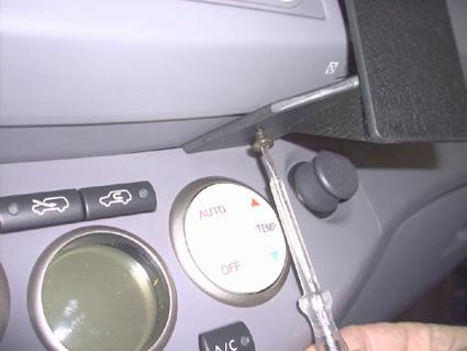 En hand håller en skruvmejsel vid en del av instrumentpanelen i en Nissan Micra.