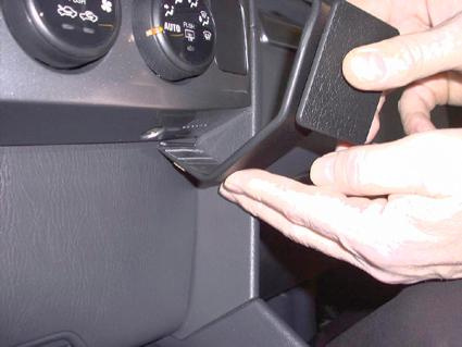 En hand monterar en del i bilen, nära instrumentpanelen.