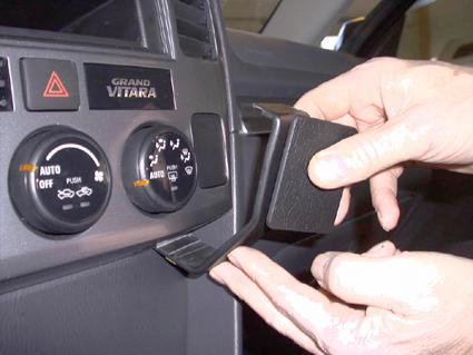 En hand som installerar en vinklad enhet i en bildashboard.