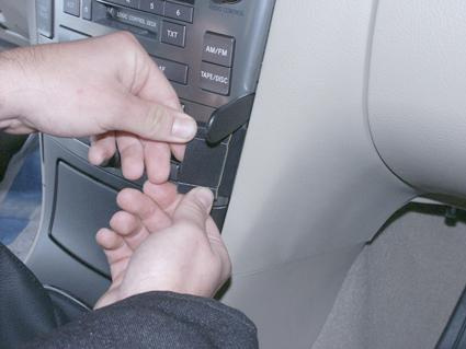 En person installerar något i instrumentbrädan på en Toyota Avensis.