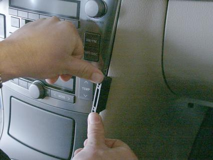 En hand som justerar en del i en bils kontrollpanel.