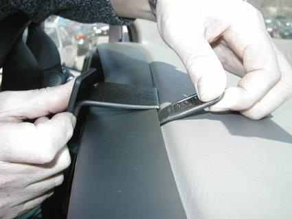 En person fäster ett spänne på insidan av en bilstol.