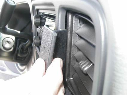 En hand som inserterar något i en bils ventilationssystem.