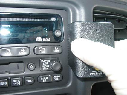 En manlig hand som håller i en svart enhet vid bilens instrumentpanel.