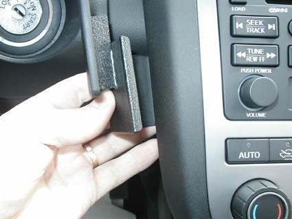 En hand håller i en del av bilens instrumentpanel, sannolikt en knapp eller fäste.