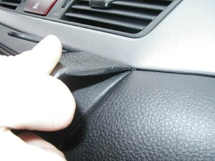 En hand som lyfter en del av instrumentpanelen i en Mitsubishi Lancer 04-07.