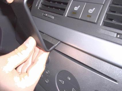 En hand som tar bort en panel från Opel Meriva instrumentbräda.