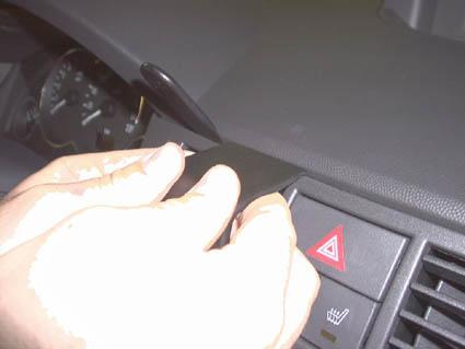 En hand som tar bort en del från instrumentpanelen i en Opel Meriva.