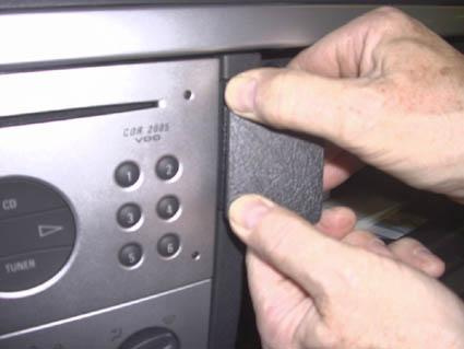 En hand sätter dit en bit plast på en bilradio i en Opel Meriva.