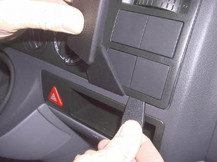 En hand tar bort en panel från instrumentbrädan i en Volkswagen Caravelle.