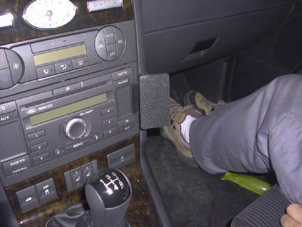 Fot på bilens interiör med växelspak och fot nära en pedal.