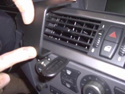 En hand pekar på en ventilationslucka och kontroller i en BMW-interiör.