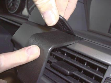 En person applicerar en centerpanel på instrumentbrädan i en BMW E60/E61.