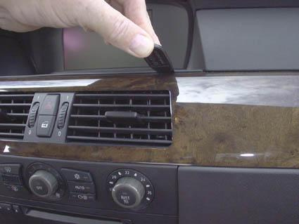 En hand som håller ett verktyg vid en luftventil i en bil.