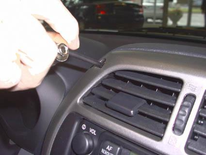 Man använder ett verktyg för att justera eller installera något i Toyota RAV4.