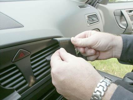 En person fäster en detalj i bilen, möjligen en del av interiören.