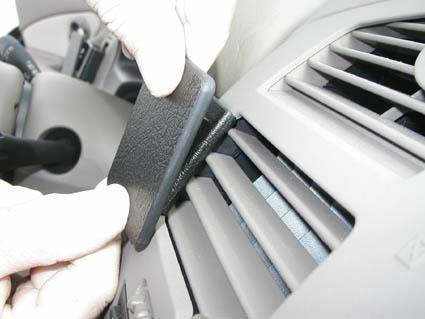 En hand placerar en svart kontakt i bilens ventilation.