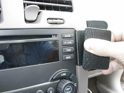 En hand håller i en svart hållare vid bilens mittkonsol.