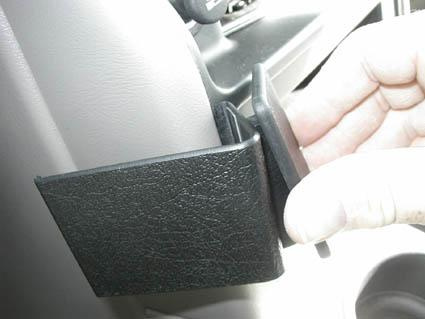 En hand håller i en svart del av en bilinteriör, troligen en tillbehörsdel.