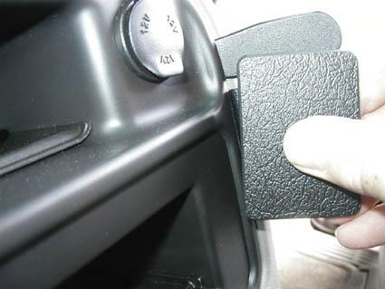 En hand håller i en låg svart knapp nära panelen i en Chevrolet Avalanche.