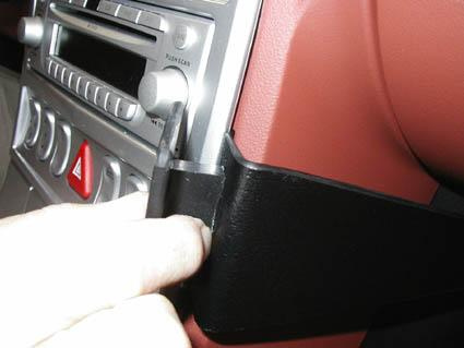 En hand justerar något vid bilens stereo- och kontrollpanel.