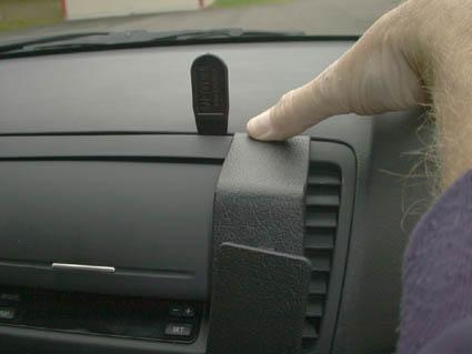 En hand trycker på en del av instrumentpanelen i en bil.