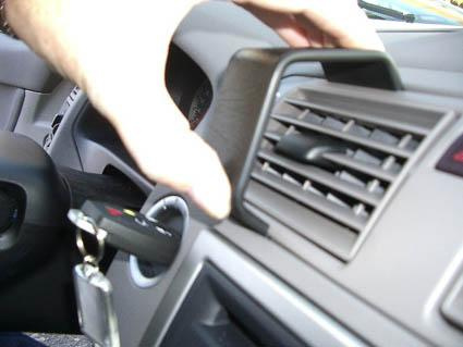 En hand justerar luftventilen i en Volvo S40. Nycklar syns i tändningslåset.