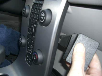 En hand håller en svart del som verkar passa i instrumentpanelen på en Volvo S40.