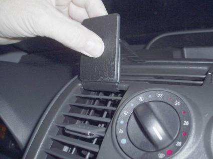 En hand placerar en svart panel på en bils luftventil.