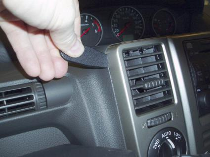 En hand håller i en del av instrumentbrädan i en Nissan X-Trail 04-07.
