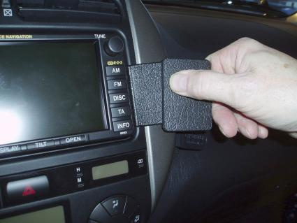 En hand håller i en svart enhet som verkar kopplas till bilens instrumentpanel.